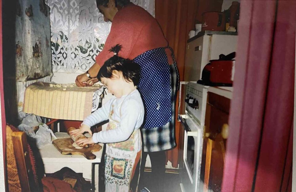 Bambina e nonna che preparano i pierogi in una cucina tradizionale.